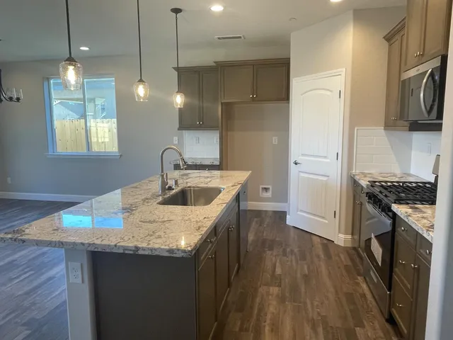 a kitchen with stainless steel appliances granite countertop a sink stove and refrigerator