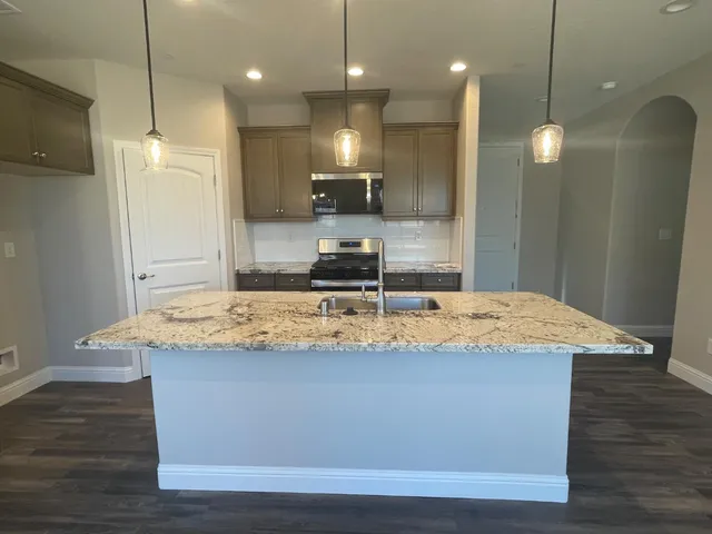 a view of a kitchen with kitchen island a island wooden floor and a refrigerator