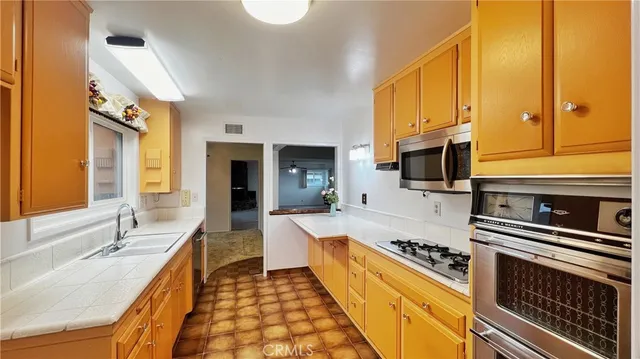a large kitchen with stainless steel appliances a stove a sink and a microwave