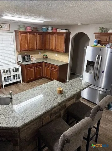 a kitchen with granite countertop a stove chairs and cabinets