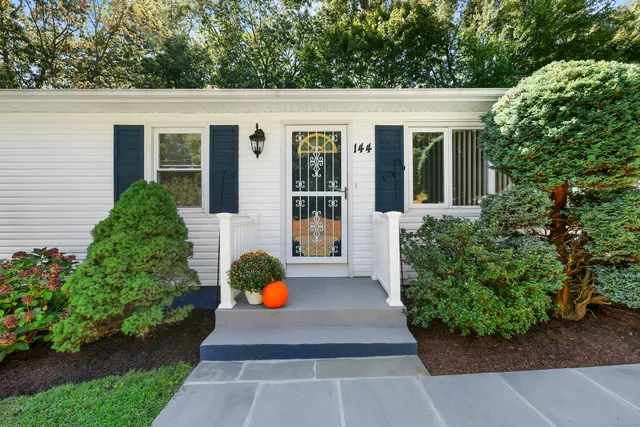 a view of a white house with a yard potted plants and seating space