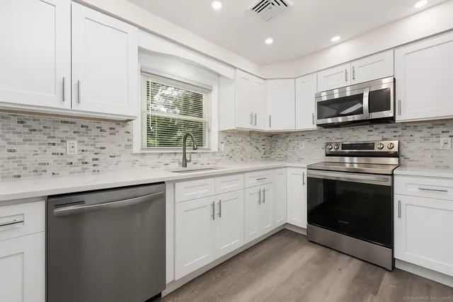 a kitchen with stainless steel appliances granite countertop a sink and a stove top oven