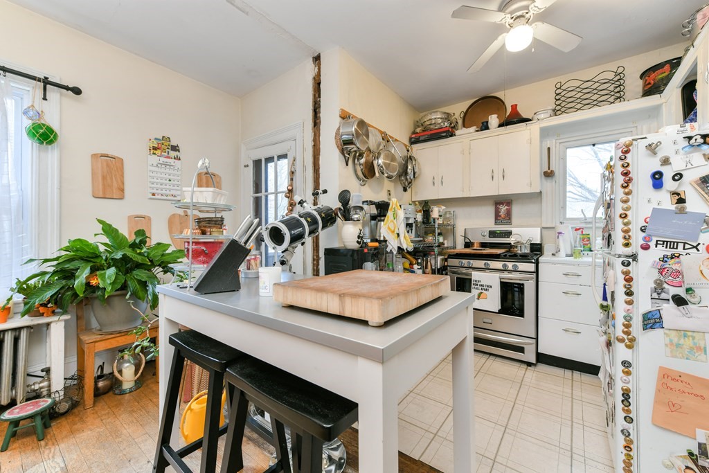 61 Montebello Road Boston, MA 02130 - Photo 20 of 35 a kitchen with stainless steel appliances kitchen island granite countertop a table chairs in it and white cabinets