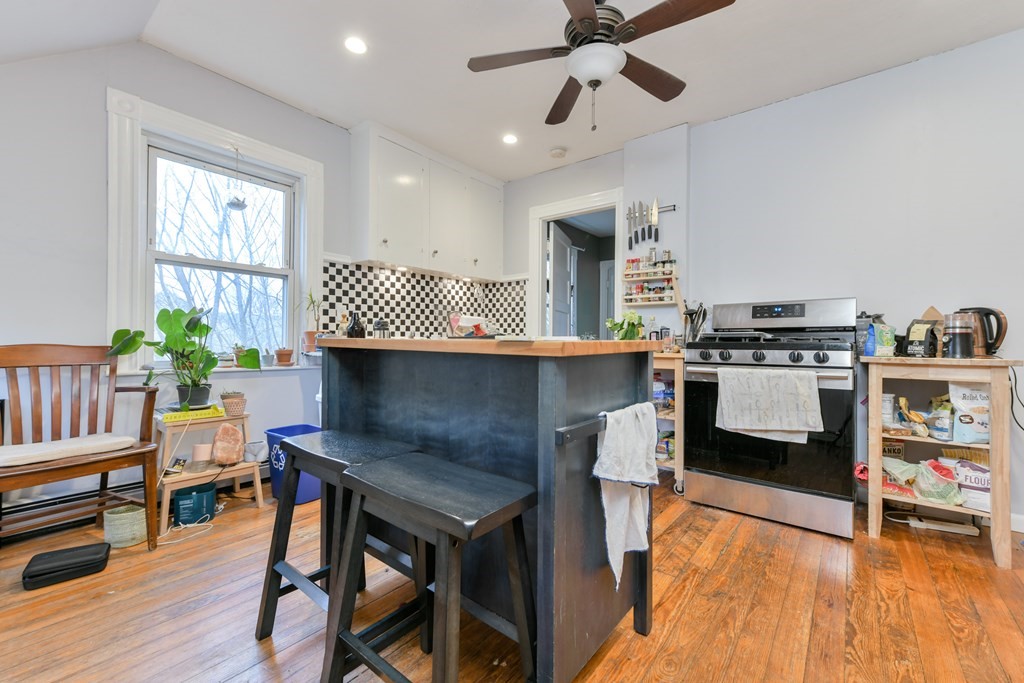 61 Montebello Road Boston, MA 02130 - Photo 30 of 35 a kitchen with stainless steel appliances granite countertop a stove top oven a dining table and chairs with wooden floor