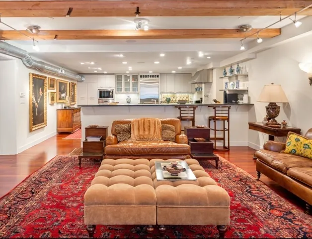 a living room with furniture kitchen view and a large window