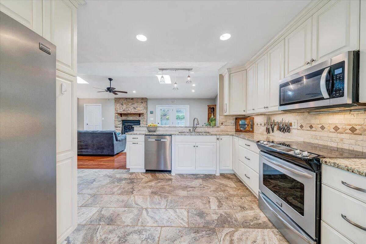 856 Ridge Mountain Drive Boones Mill, VA 24065 - Photo 11 of 66 a kitchen with stainless steel appliances granite countertop a stove top oven a sink dishwasher a refrigerator and cabinets with wooden floor