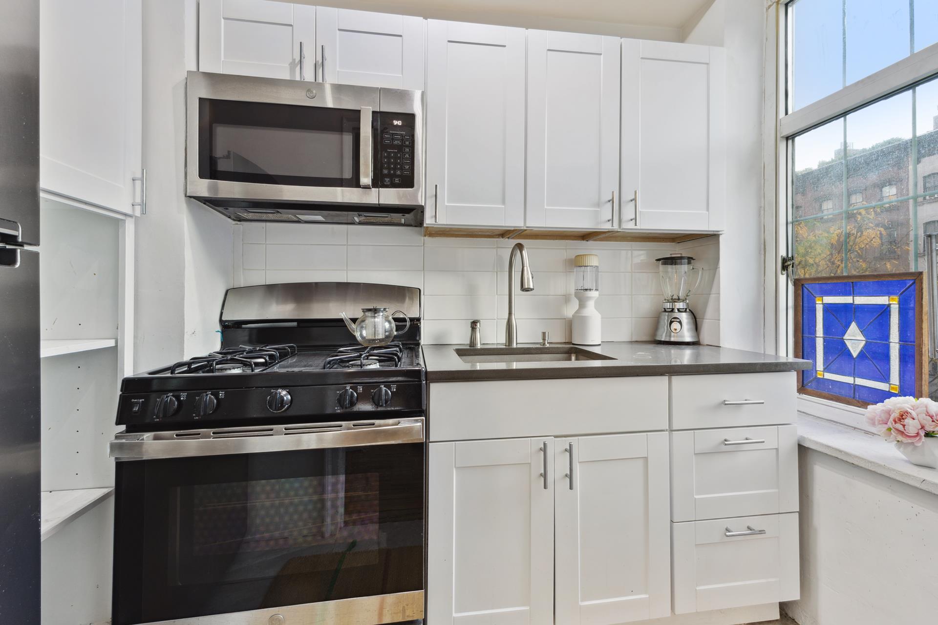 465 West 23rd Street, Unit 3C Manhattan, NY 10011 - Photo 4 of 32 a kitchen with white cabinets and black appliances