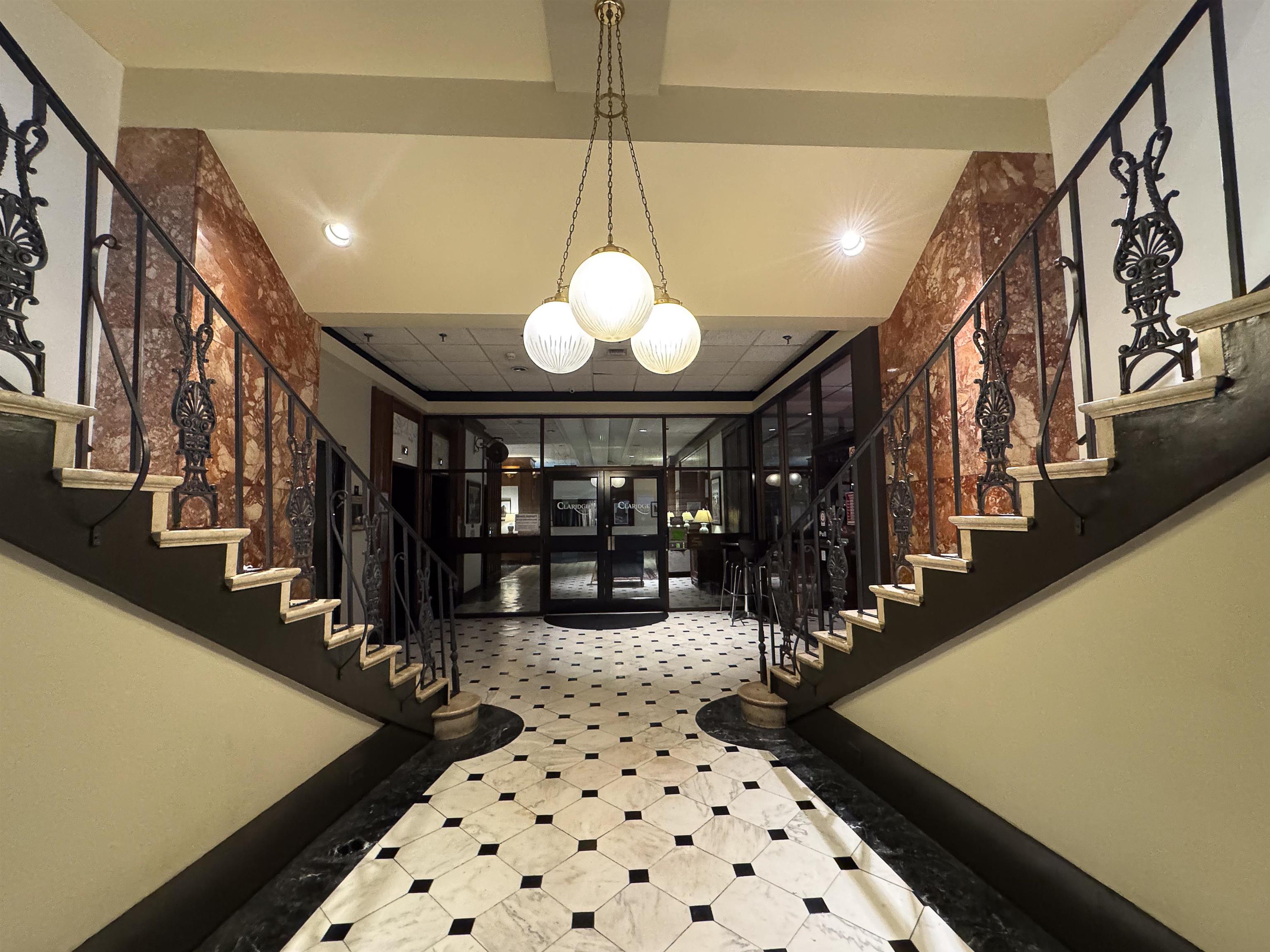 109 North Main Street, Unit 907 Memphis, TN 38103 - Photo 22 of 29 Grand foyer featuring a checkerboard tile floor, ornate iron railings, and extensive red-veined stone wall cladding