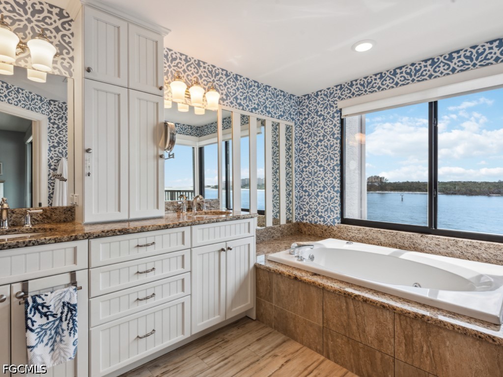232 La Peninsula Boulevard, Unit 232 Naples, FL 34113 - Photo 17 of 44 a bathroom with a granite countertop sink mirror and a bathtub