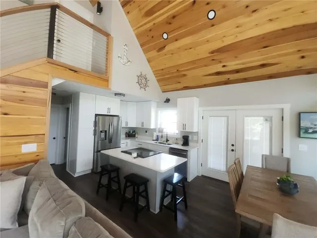 a kitchen with stainless steel appliances kitchen island granite countertop a table chairs in it and wooden floors