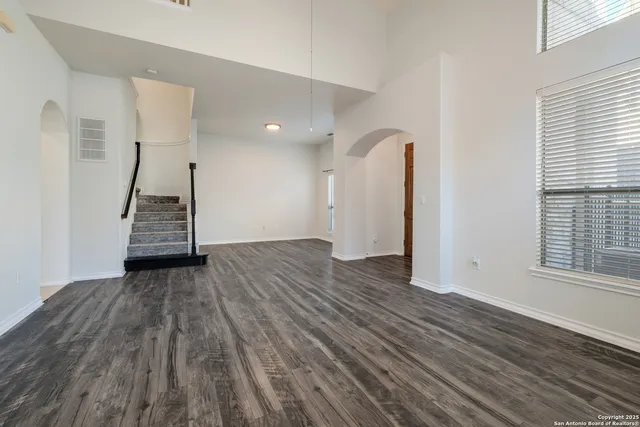 a view of an empty room with wooden floor and stairs
