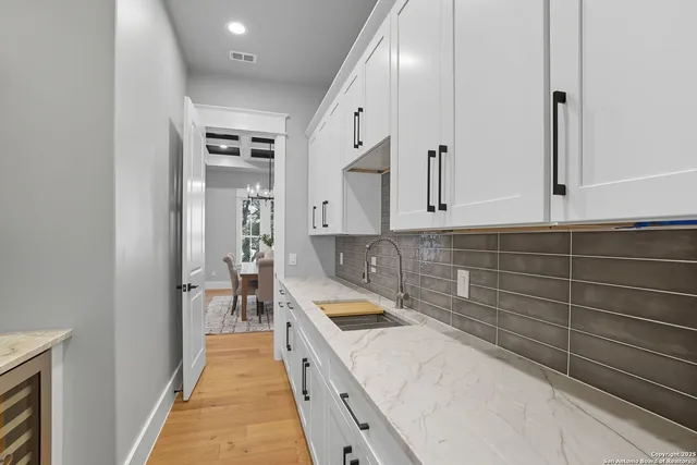 a large white kitchen with sink and stainless steel appliances