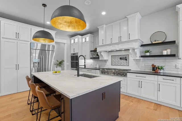 a kitchen with stainless steel appliances granite countertop a sink a stove and cabinets