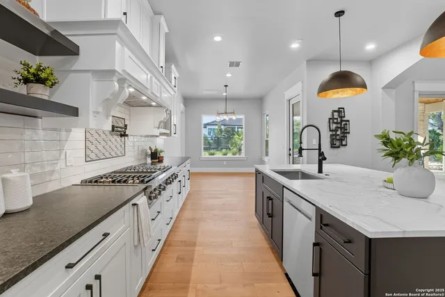 a spacious kitchen with stainless steel appliances granite countertop a sink a stove and a wooden floors