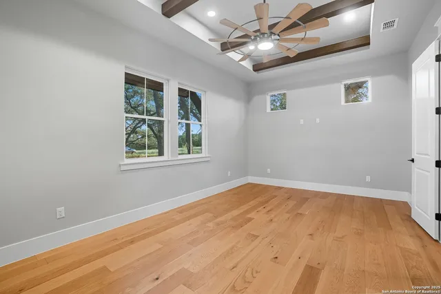 a view of empty room with wooden floor and fan