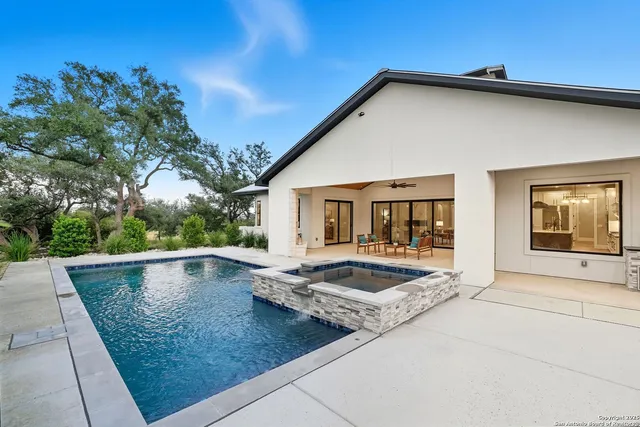 a view of a house with pool fire pit and couches under an umbrella