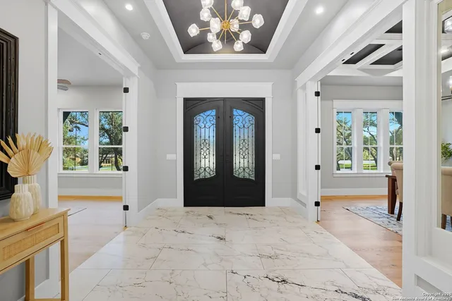 a view of a hallway with windows and chandelier