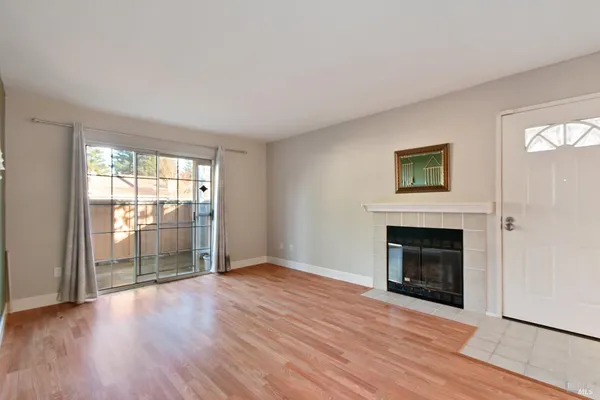 an empty room with wooden floor fireplace and windows