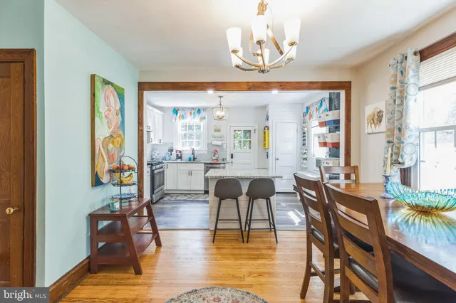 a view of a dining room with furniture one side kitchen view and wooden floor