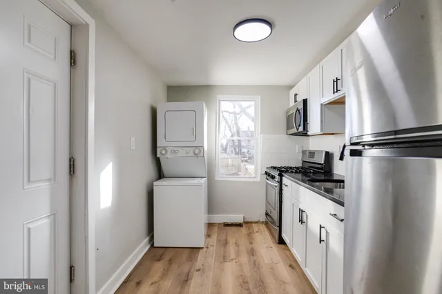 a kitchen with granite countertop a refrigerator a sink a stove and wooden floor