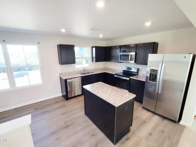 a kitchen with stainless steel appliances granite countertop a refrigerator a sink a stove a microwave and island