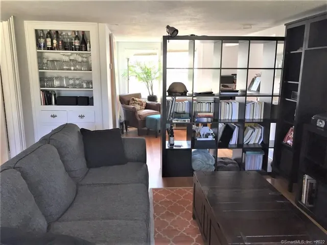 a living room with furniture large window and wooden floor