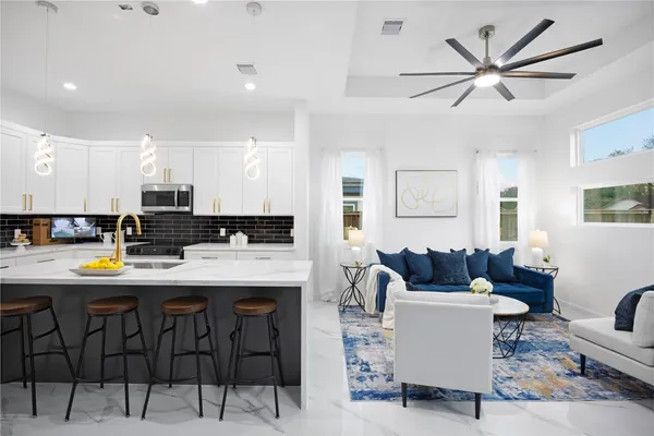 a kitchen with stainless steel appliances kitchen island granite countertop a dining table chairs and a refrigerator