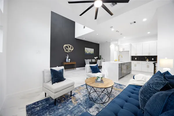 a living room with furniture kitchen view and a chandelier