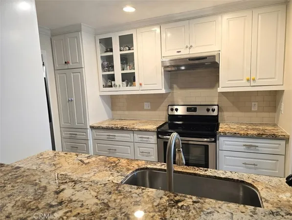 a kitchen with granite countertop a sink and a stove