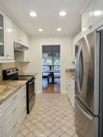 a kitchen with granite countertop a refrigerator and a stove top oven