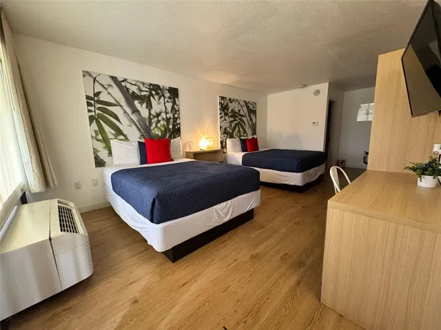 a bedroom with a bed and a flat tv screen on the dresser