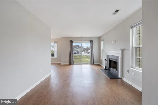 an empty room with fireplace wooden floor and windows