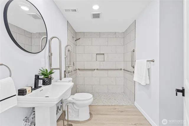 a bathroom with a sink a mirror a toilet and a shower