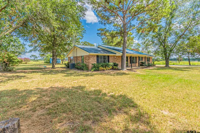a front view of a house with swimming pool and trees