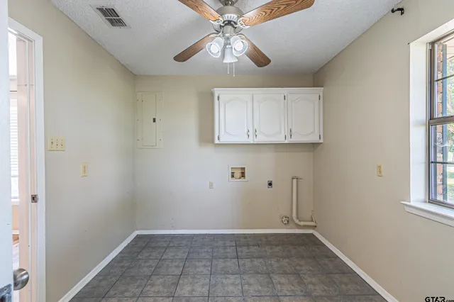 a view of an empty room with wooden floor and a ceiling fan