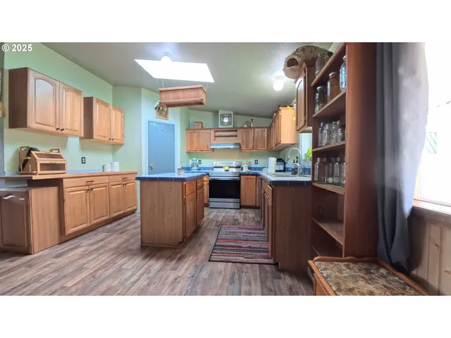 a kitchen with stainless steel appliances kitchen island granite countertop a sink refrigerator and cabinets