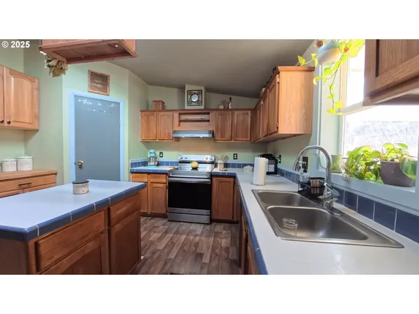 a kitchen with a sink a counter top space a stove and cabinets