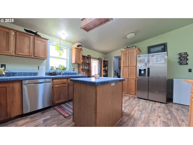 a kitchen with granite countertop a refrigerator and wooden cabinets