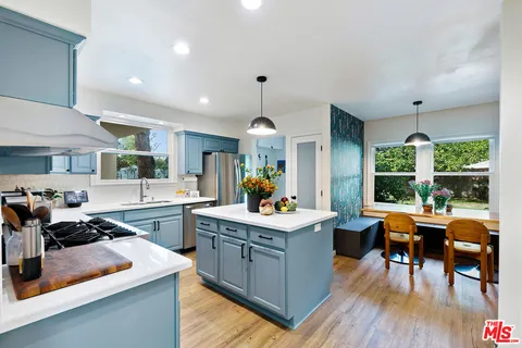 a kitchen with stainless steel appliances granite countertop a stove oven and a dining table with wooden floor