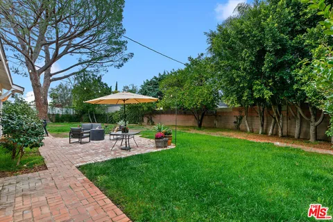 a view of backyard with table and chairs under an umbrella