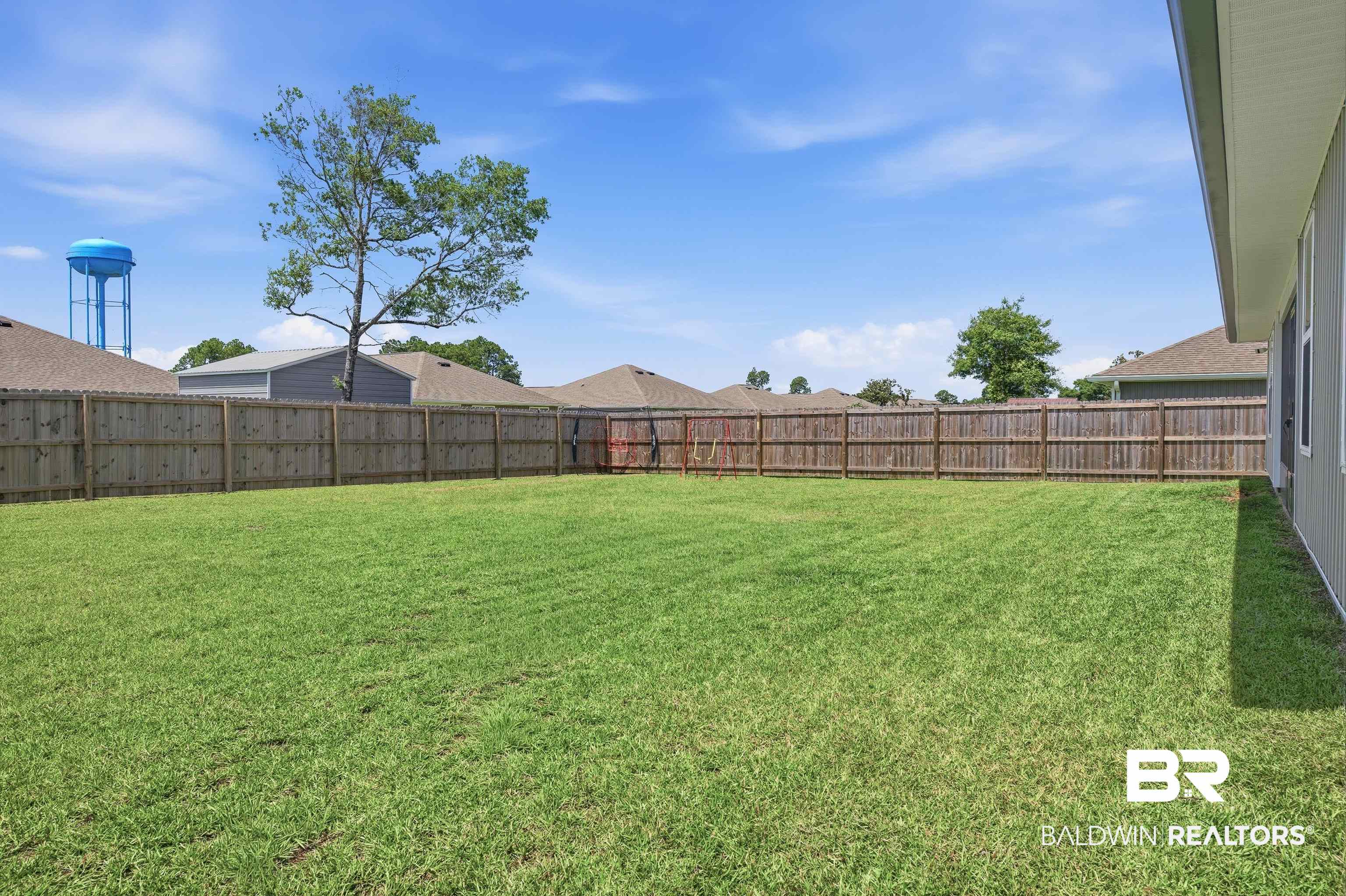 3213 Camino Real Loop Lillian, AL 36549 - Photo 9 of 61 Expansive green lawn featuring a full wood privacy fence and a light-colored exterior wall with windows
