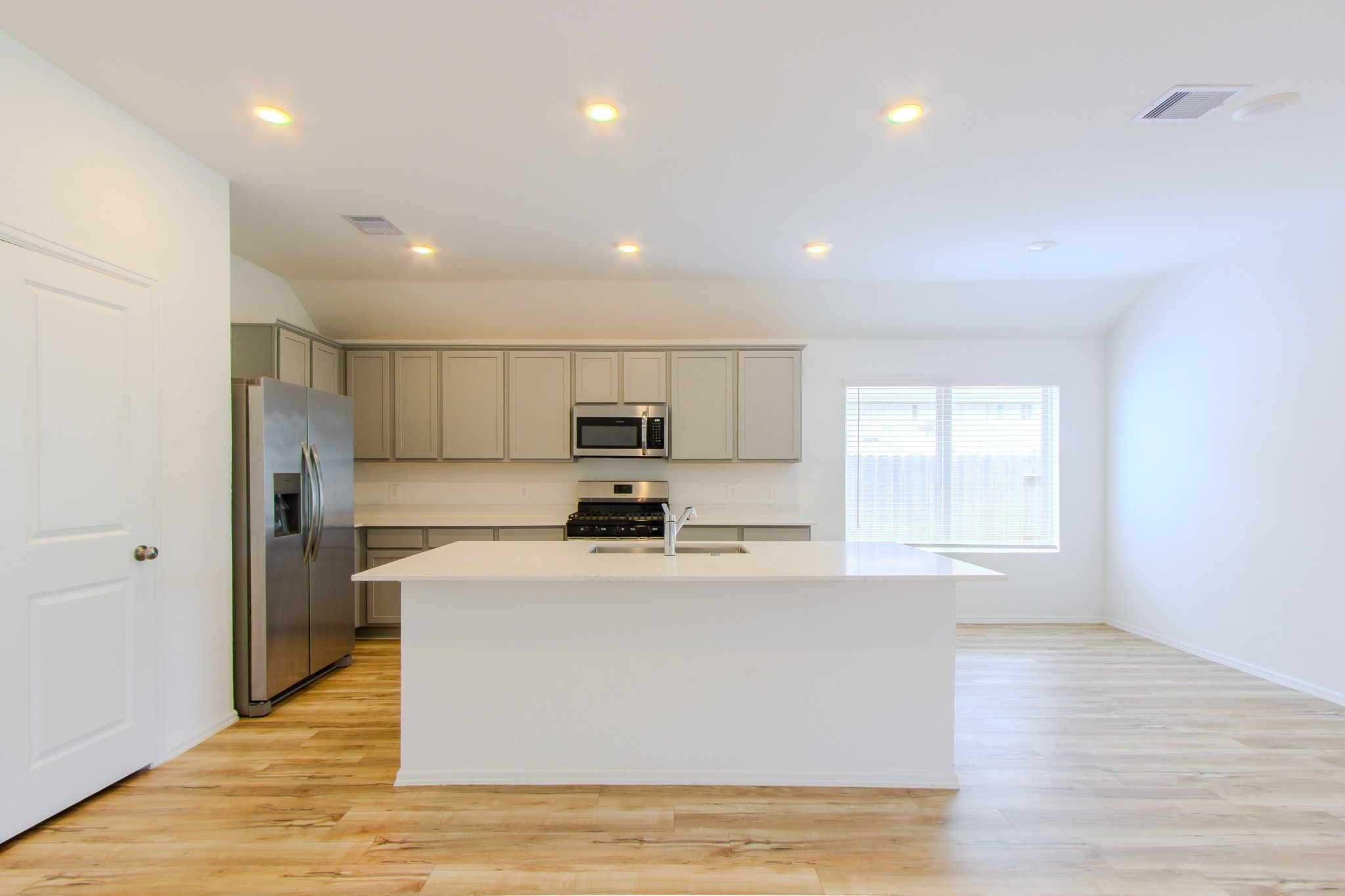 3113 Catalonion Court Conroe, TX 77301 - Photo 8 of 45 a view of a kitchen with stainless steel appliances granite countertop a stove a sink a refrigerator white cabinets and wooden floor