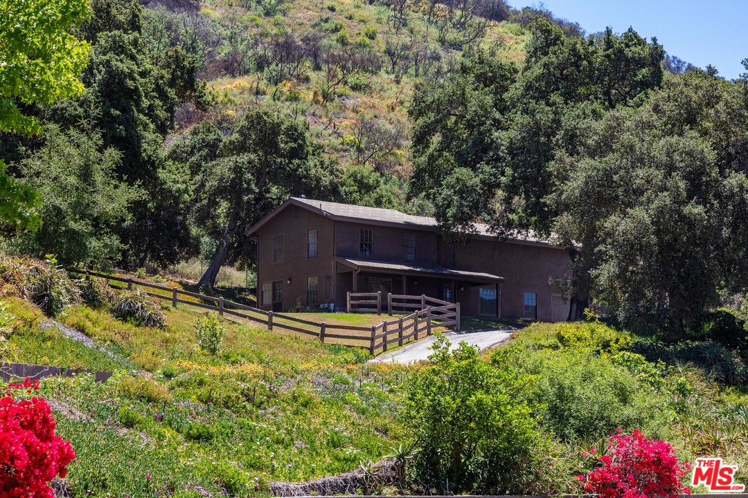 3100 Mandeville Canyon Road Los Angeles, CA 90049 - Photo 15 of 27 a backyard of a house with table and chairs and wooden fence