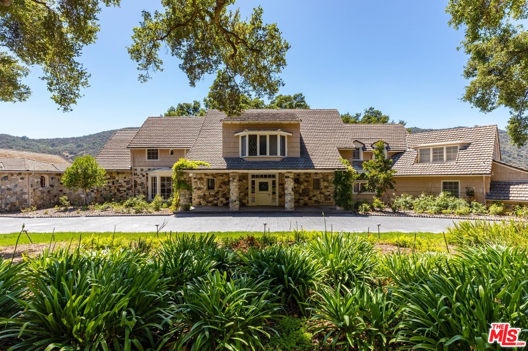 3100 Mandeville Canyon Road Los Angeles, CA 90049 - Photo 18 of 27 a view of a house with a big yard and potted plants