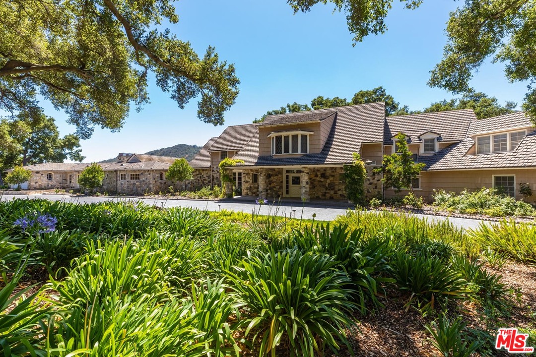 3100 Mandeville Canyon Road Los Angeles, CA 90049 - Photo 19 of 27 a view of a house with a yard and potted plants