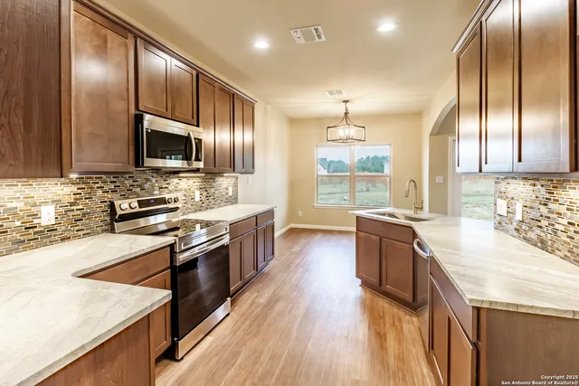 a large kitchen with stainless steel appliances granite countertop a stove a sink and a refrigerator