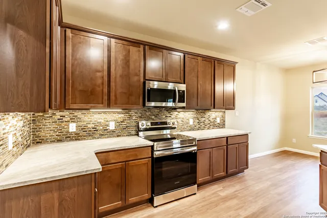 a kitchen with stainless steel appliances wooden cabinets and a stove top oven