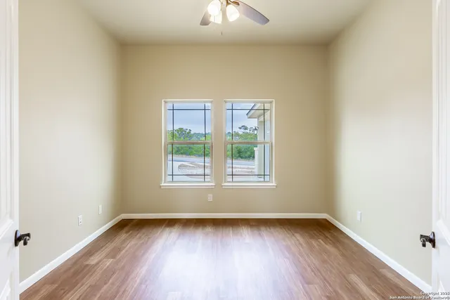 an empty room with wooden floor and windows