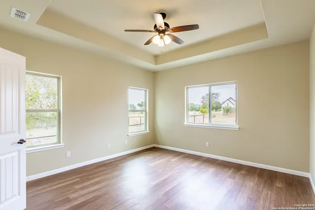 a view of an empty room with a window and wooden floor