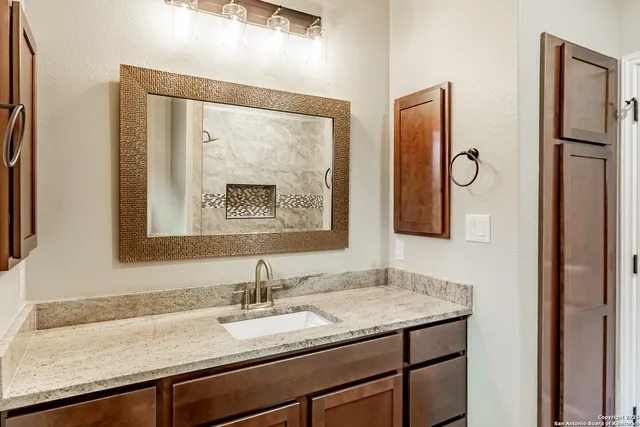 a bathroom with a granite countertop sink and a mirror